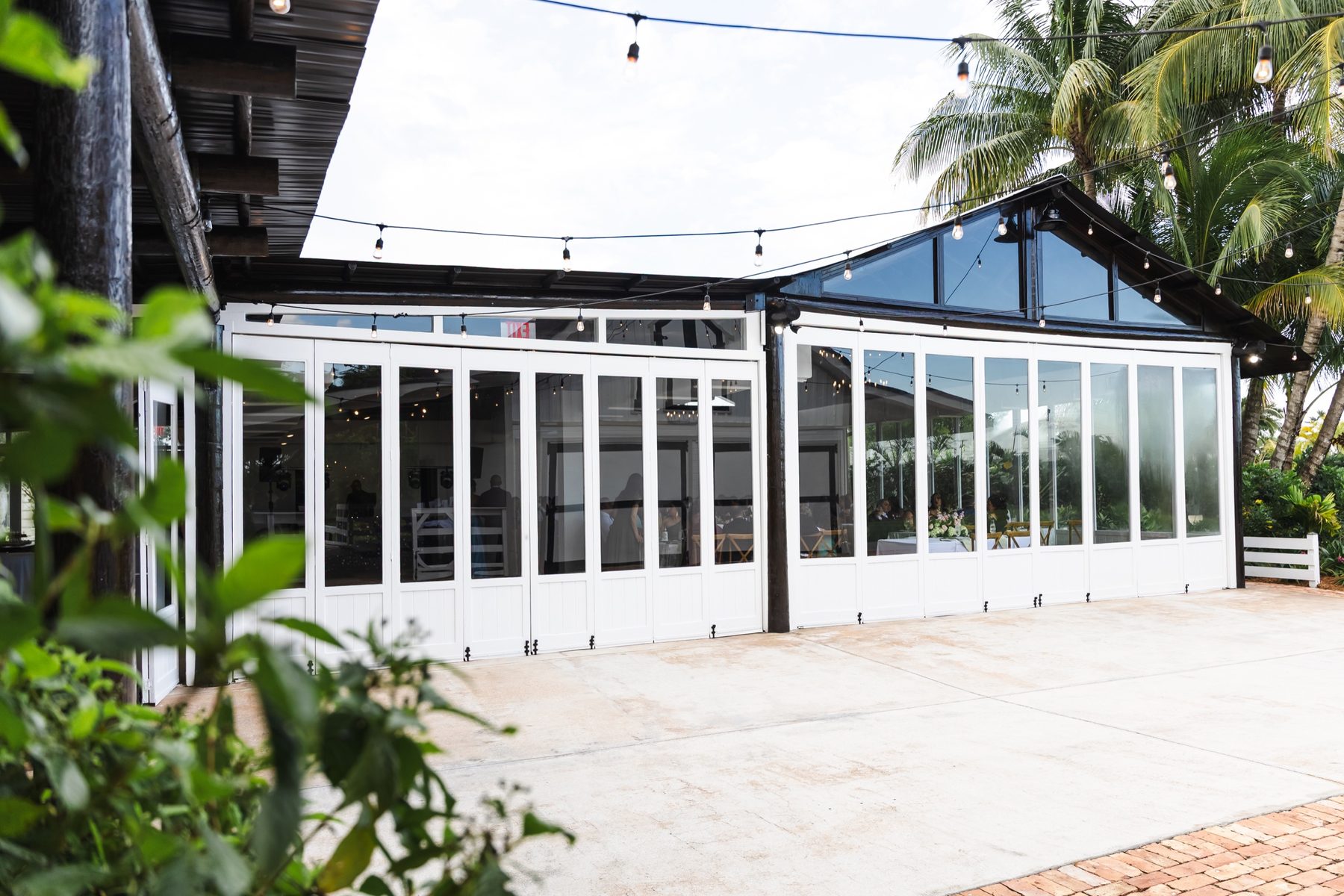The glass-lined exterior of The Estate Room surrounded by tropical landscaping