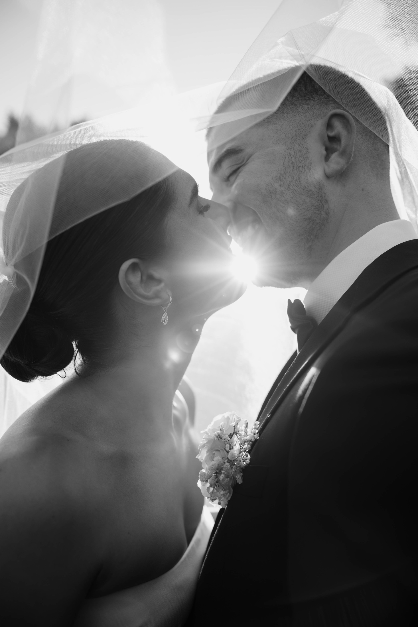 A newlywed couple sharing a quiet moment beneath the bride's veil