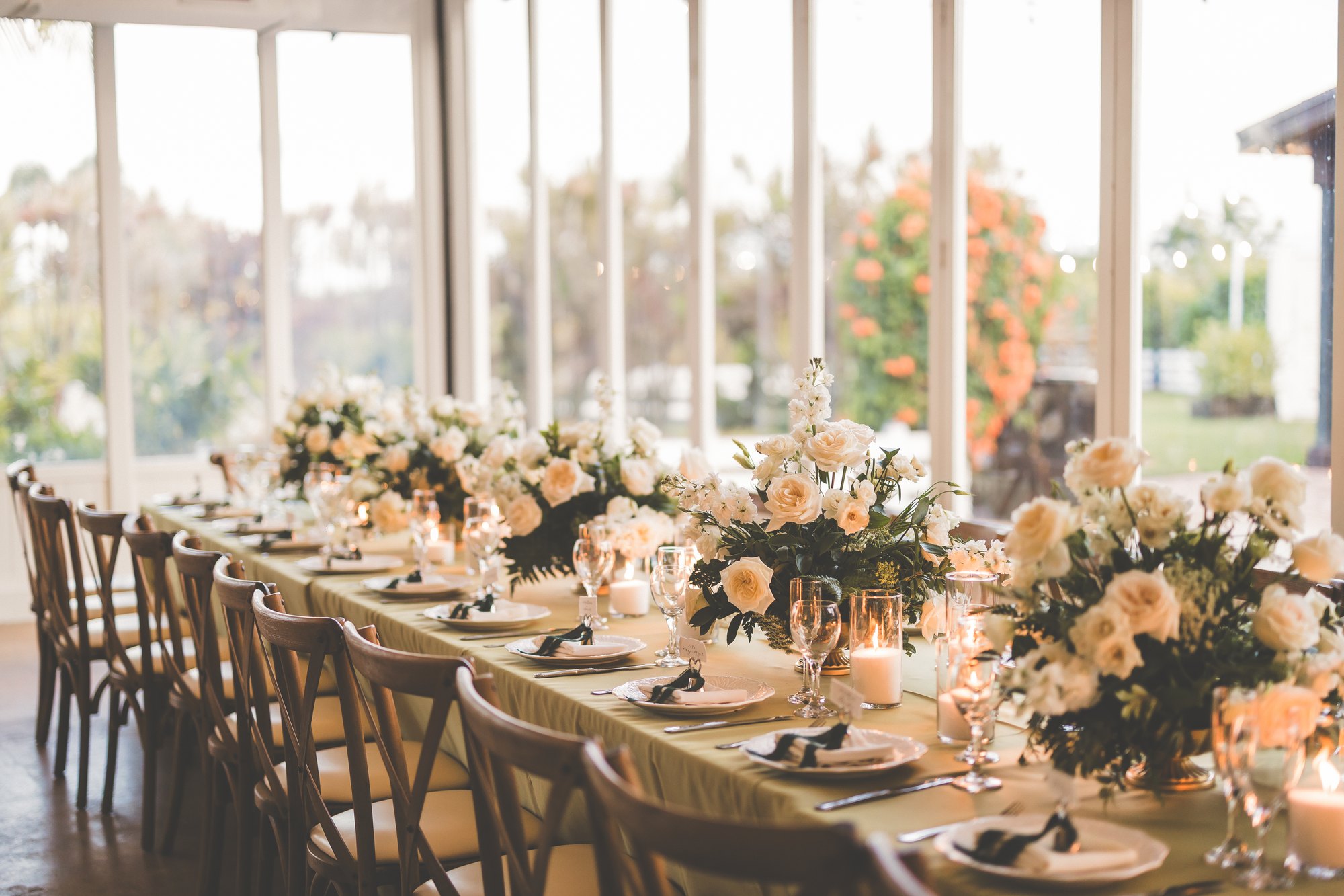 A candlelit wedding dinner arranged with florals inside the glass-lined Estate Room